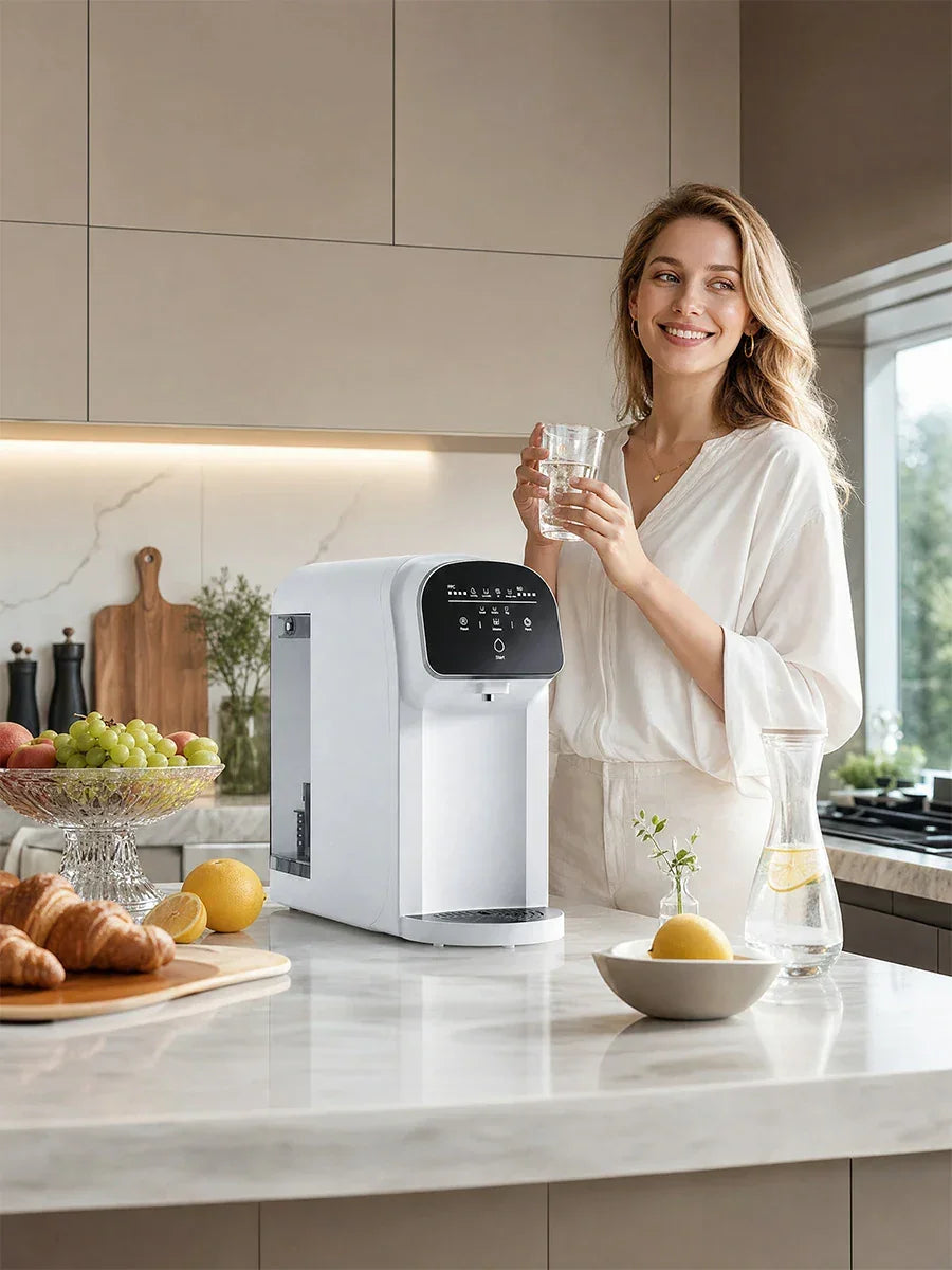 Woman holding glass of purified water beside countertop water filter with UV sterilization in modern kitchen